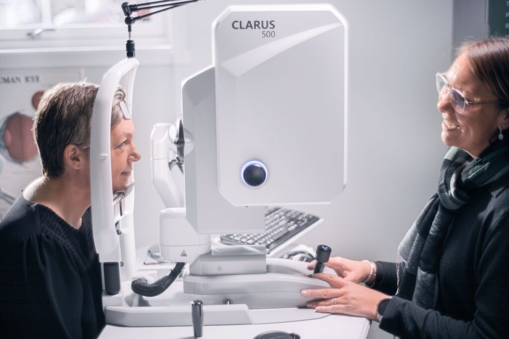A woman looking examining a patient's eyes using a machine